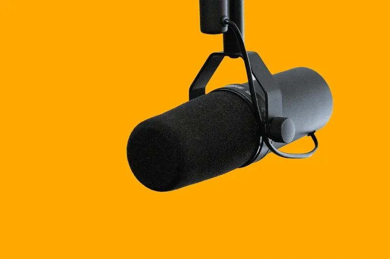 A studio microphone on an orange background
